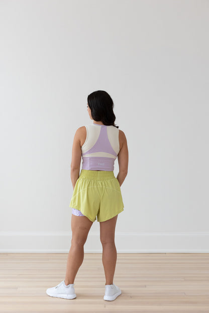 Back view of EMIÉ Just Run Crop Tank in lilac - women's running top with back pocket detail