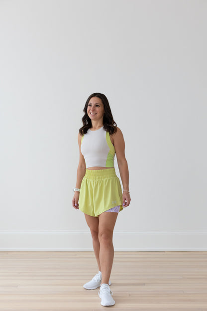 Woman in EMIÉ key lime crop tank and Problem Solved running shorts - matching women's running outfit