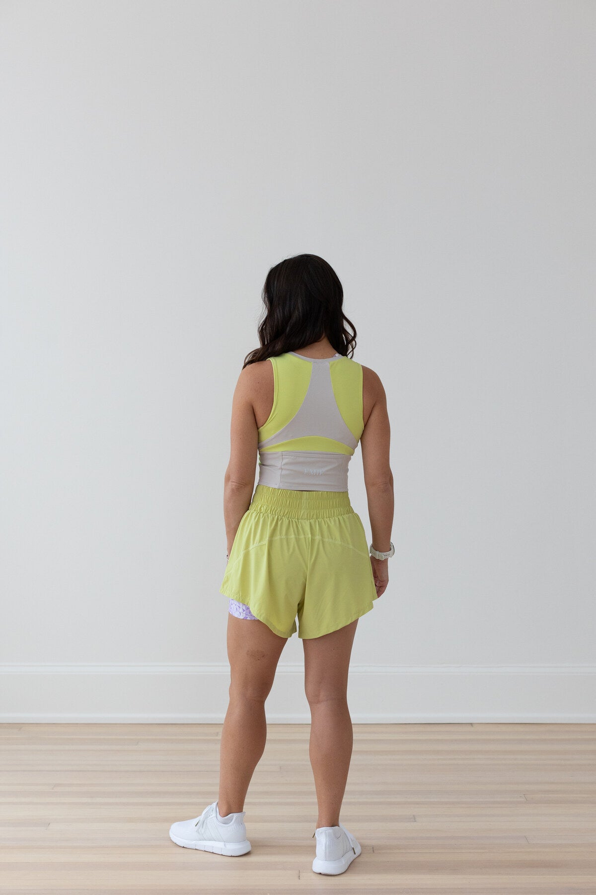 Woman in EMIÉ key lime crop tank and Problem Solved running shorts - matching women's running outfit