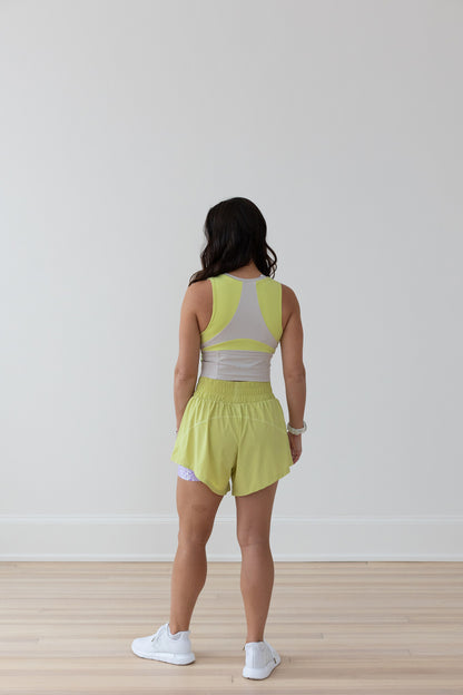 Woman in EMIÉ key lime crop tank and Problem Solved running shorts - matching women's running outfit